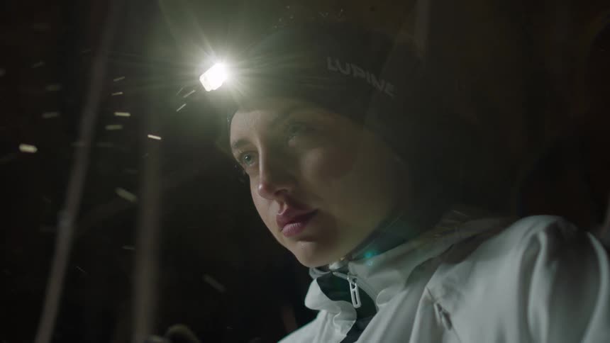 A woman warms up outside in the snow and turns her head lamp light to red