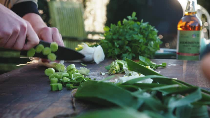 A person is cutting leeks with a knife