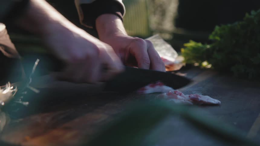 Man opens a packet of bacon and slices it into pieces
