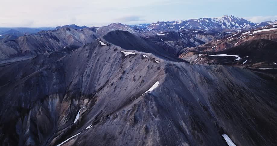 An aerial view of a mountain range with some mountains with some snow on the peak