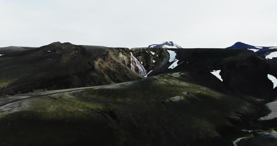 A rugged landscape with a waterfall cascading down a mountainous terrain