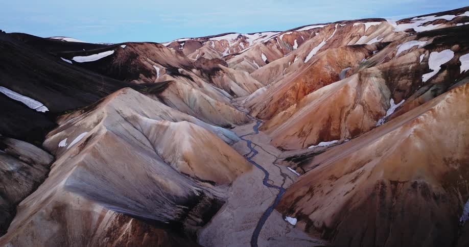 Streams flow through a narrow valley in mountainous terrain during winter