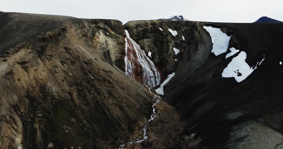 A small waterfall that comes out of rocks on top of a hill