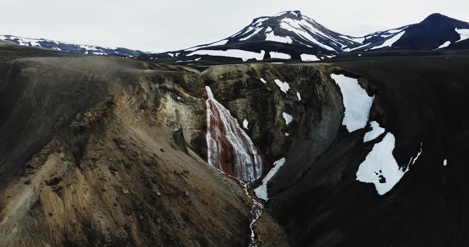Aerial of a cascading waterfall that flows into a canyon