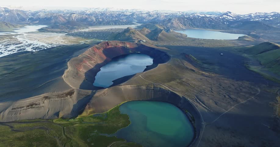 Streams and crater lakes fill the terrain bordering snowy mountains