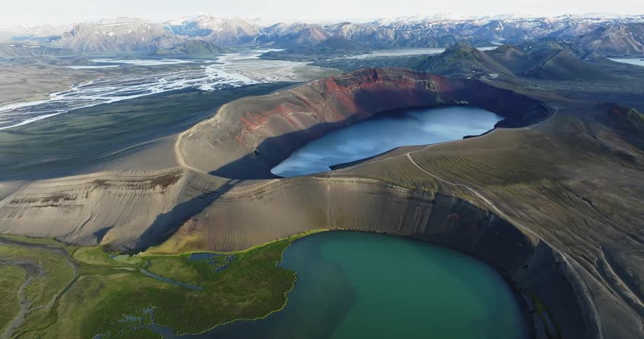 Streams fill the plain between crater lakes and a snowy mountain range
