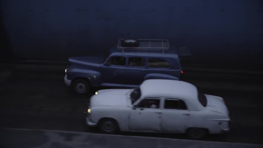 Two cars drive side by side on a road