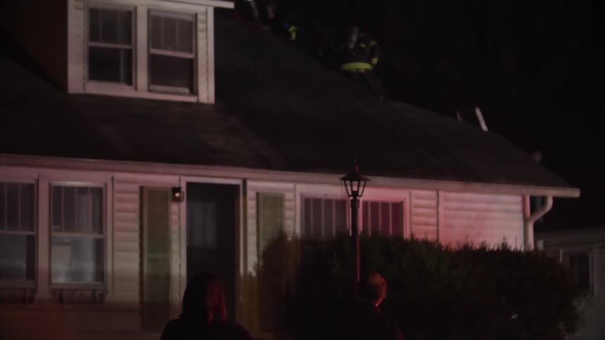 Couple watches firemen on roof at night