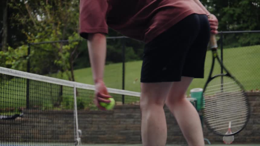 Boy catching a tennis ball on the court with his racket