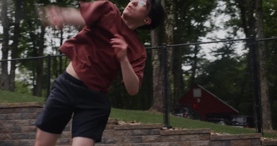 Teenage boy serves a tennis ball on a basketball court