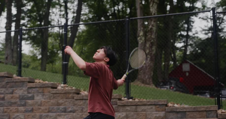 Teenager throwing a green ball with a racket in a tennis game