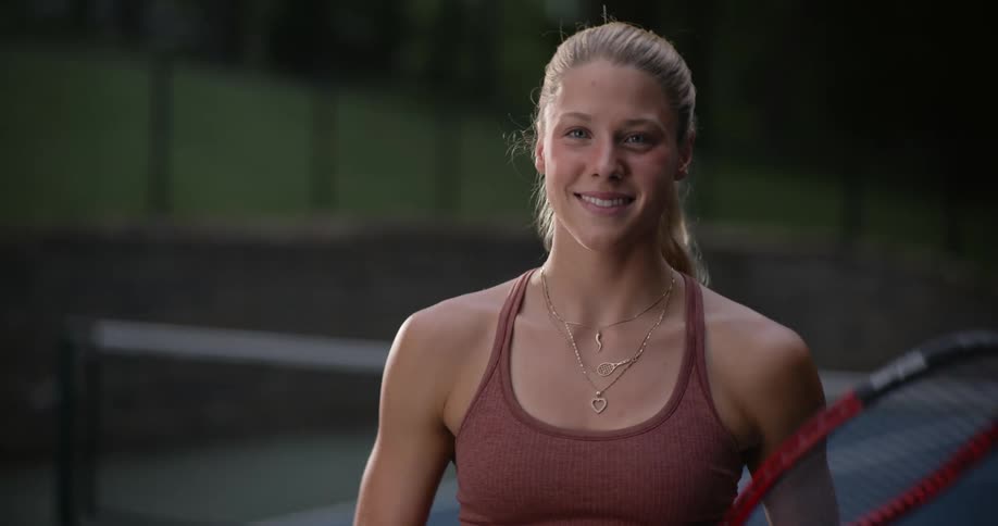 Happy blonde woman on a court spinning tennis racket