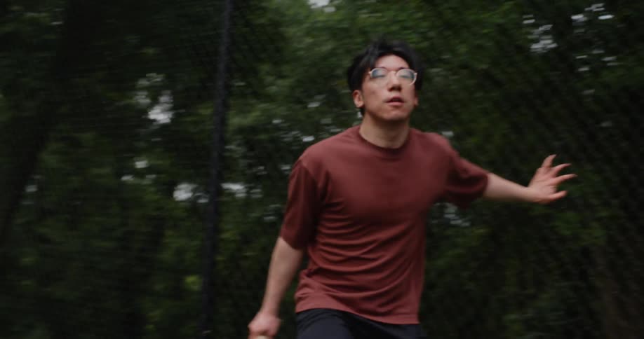 Teenage boy runs back and forth a court to hit a tennis ball