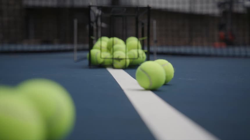 Several green tennis balls falling on a blue floor with a white line in the center