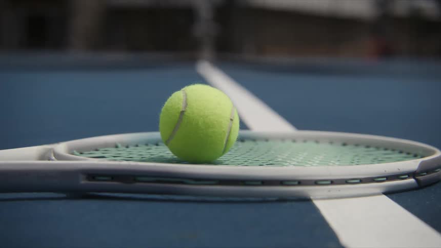 A tennis ball on a racket and both on the tennis courts floor then theyre taken away