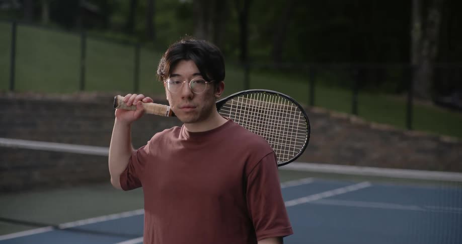 A man points a tennis racket at the camera