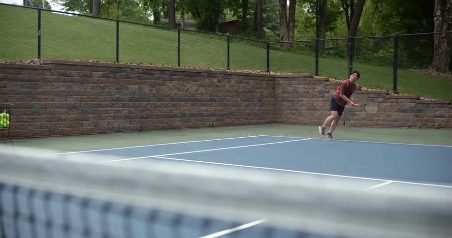 Teenage boy judging tennis on an open court with trees in the background
