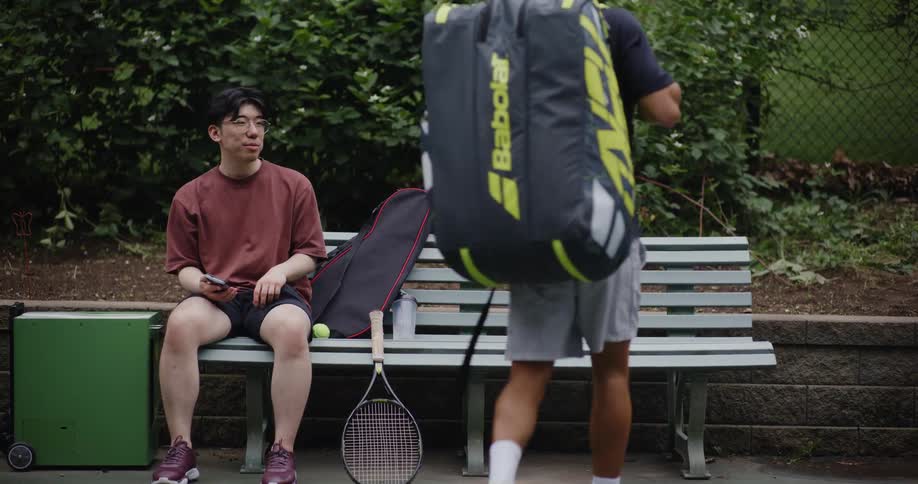 Two tennis players talk at a courtside bench