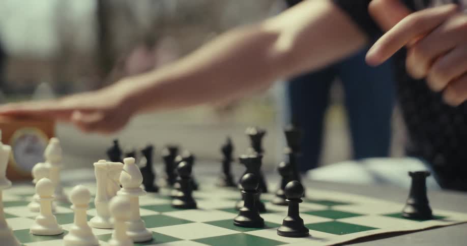 A man moves a black chess piece and hits the timer