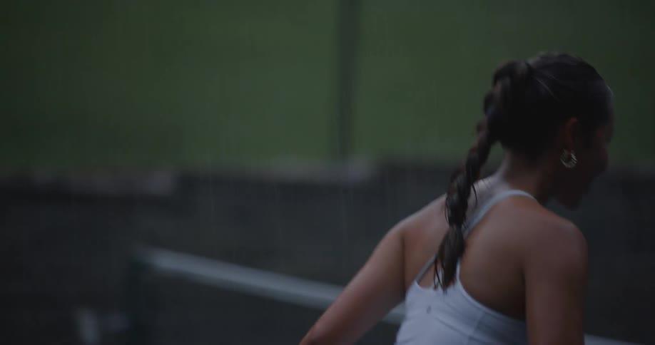 A young asian girl plays tennis on a court in a park