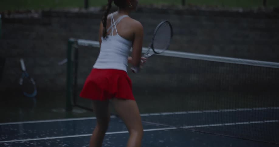 Woman on a court playing tennis on a rainy day