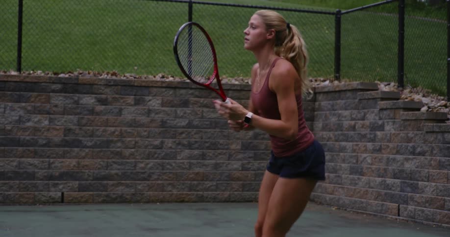 Young blonde woman playing tennis on an open court