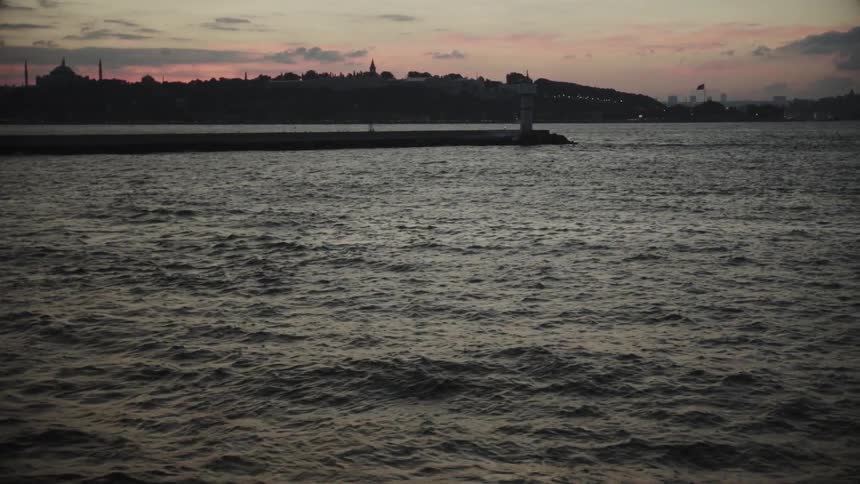 Semi-calm waters showing a colorful sunset behind the land