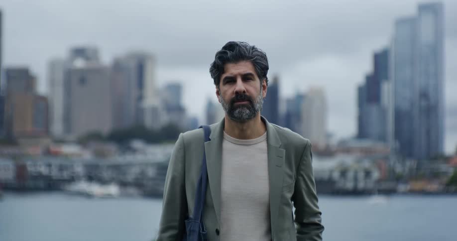 An older gentleman stands in front of a city skyline