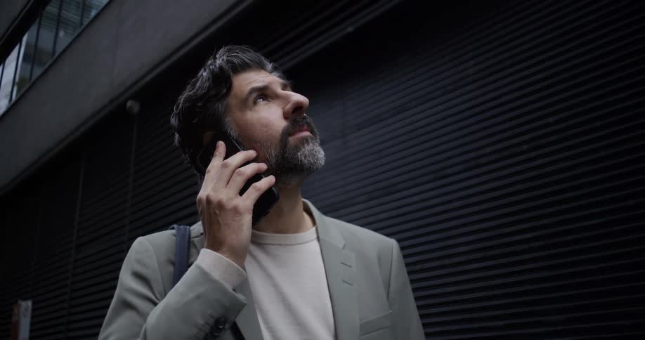 Portrait of a man in a suit in an outdoor setting answering a smartphone