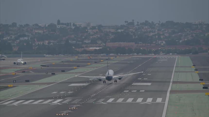 A large jet passenger plane executes a landing at an airport near a suburb