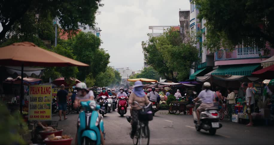 Customers shop for food and other items at street markets near a busy street