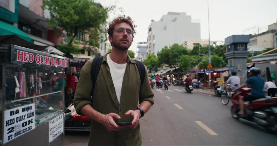 Man looks lost while looking around the city and at his phone