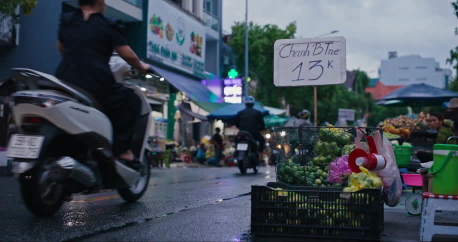 Wet street with motorcycle traffic and food and fruit markets around