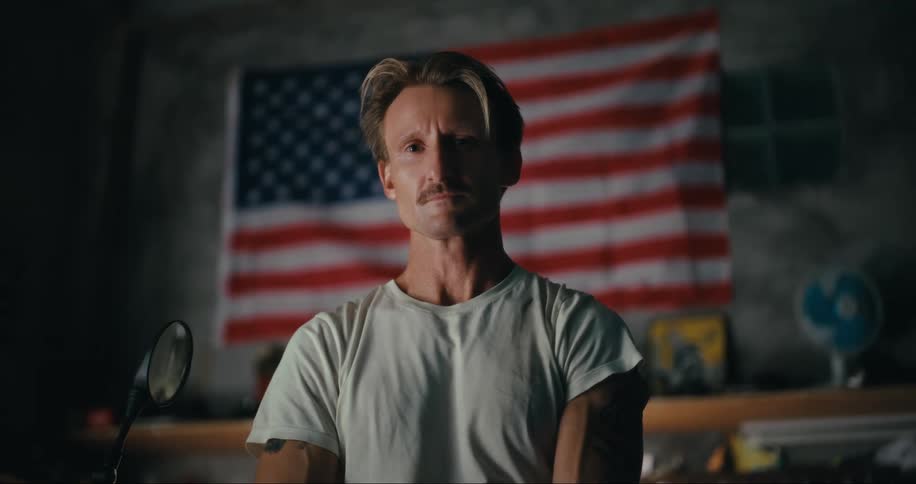Portrait of a blond man with the united states flag in the background on a wall
