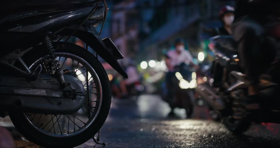 Wet street seen at night with heavy motorcycle traffic