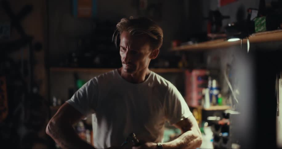 A man tries to find the right attachment for a hand tool while standing in a garage