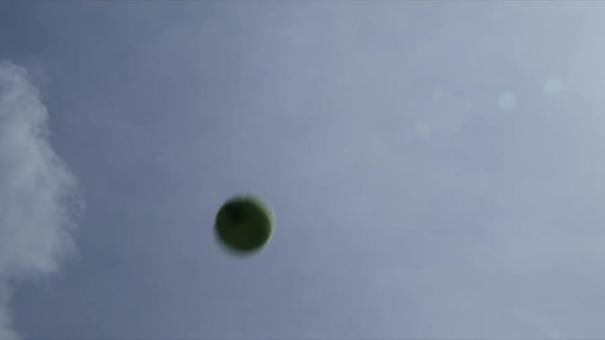 A green tennis ball thrown up into the air