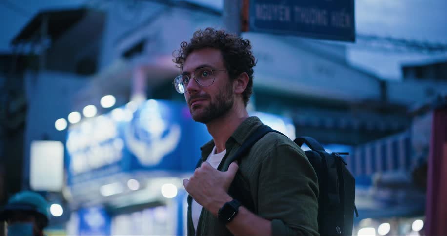 Tourist man wearing a backpack on a busy street in the late afternoon
