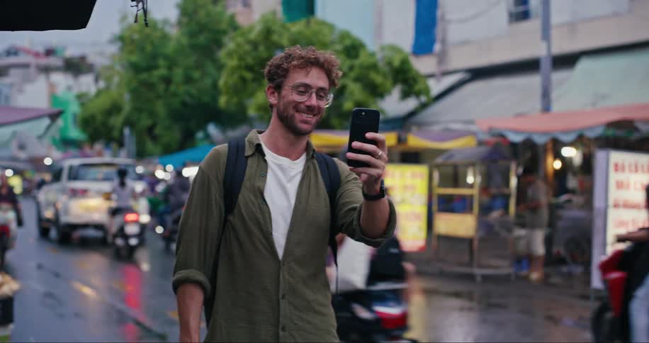 Smiling man on a busy street using his cell phone