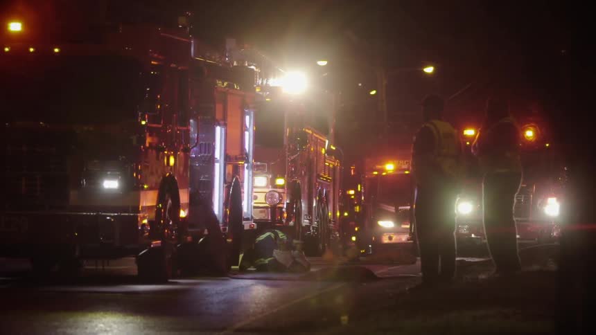 A line of emergency vehicles parked on the road at night