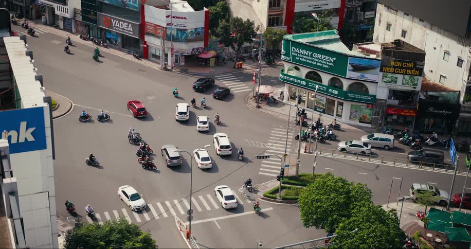 An intersection of asphalt streets with a lot of motorcycle and car traffic