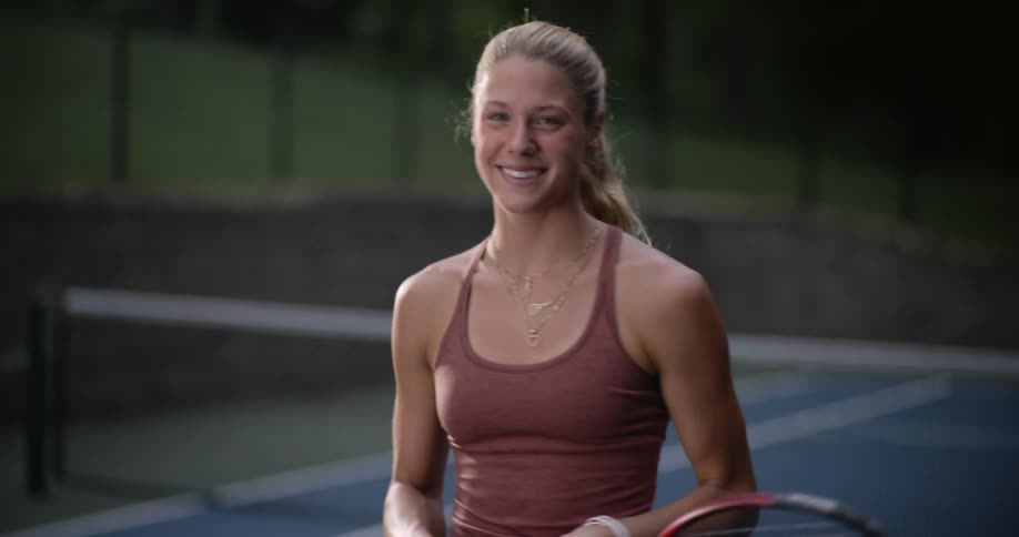 Portrait of a smiling woman as the tennis racket on the court