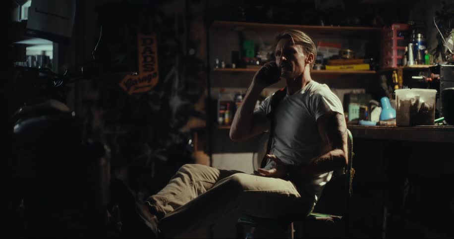 Man sitting on a chair in a garage talking on his cell phone