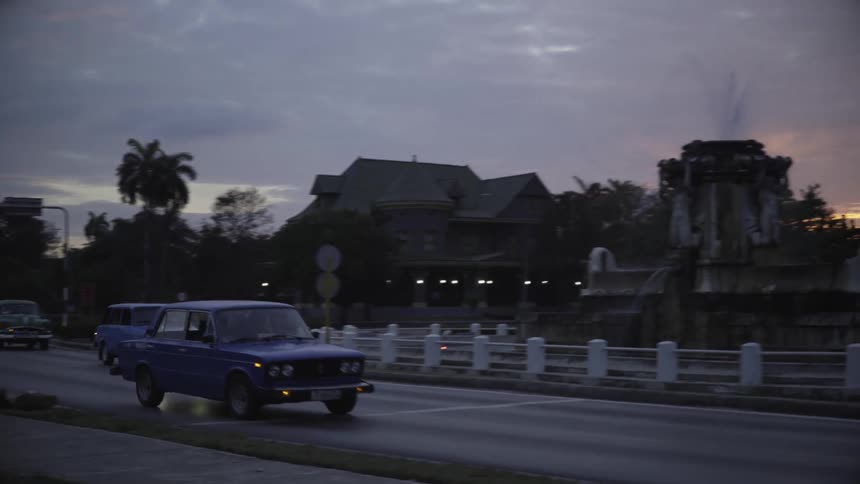 Cars drive on a busy street at dusk