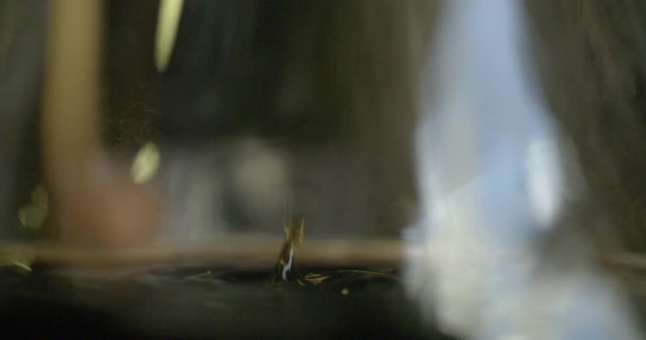 Drops of liquid falling into water and splashing upwards