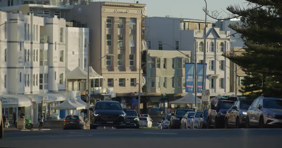 A city street scene with cars and a motorbike rider surrounded by tall buildings