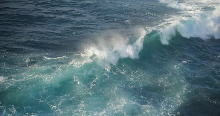 Aerial view of large ocean waves crashing on a coast