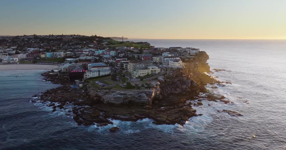A coastal city with waves crashing on the rocks near the residences