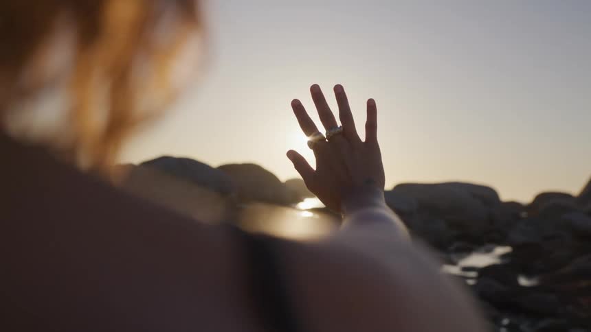 A woman blocks the bright sun with her hand