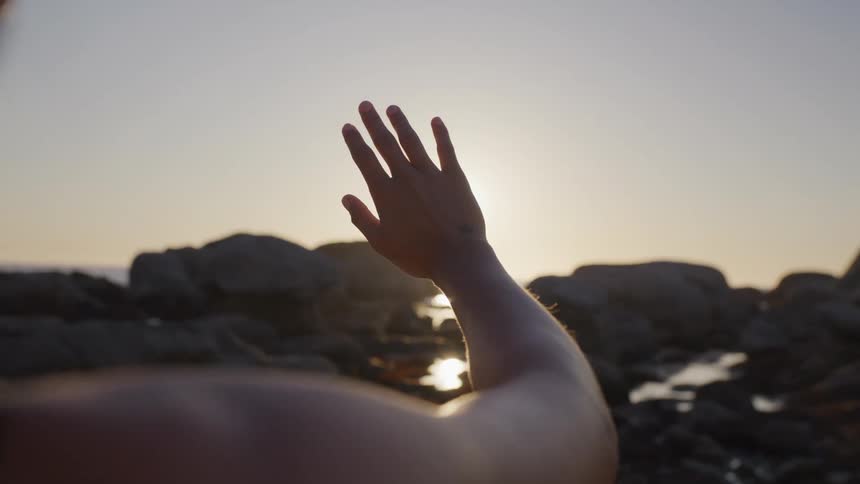 Womans hand against the sunset in a natural environment